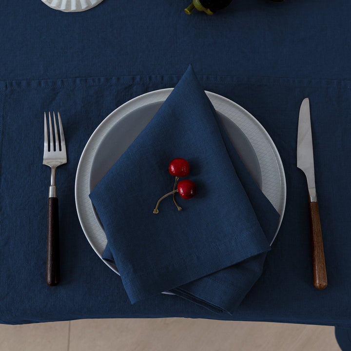 Square 20x20 inch navy linen napkin, styled with crisp white plates for a nautical-inspired look.